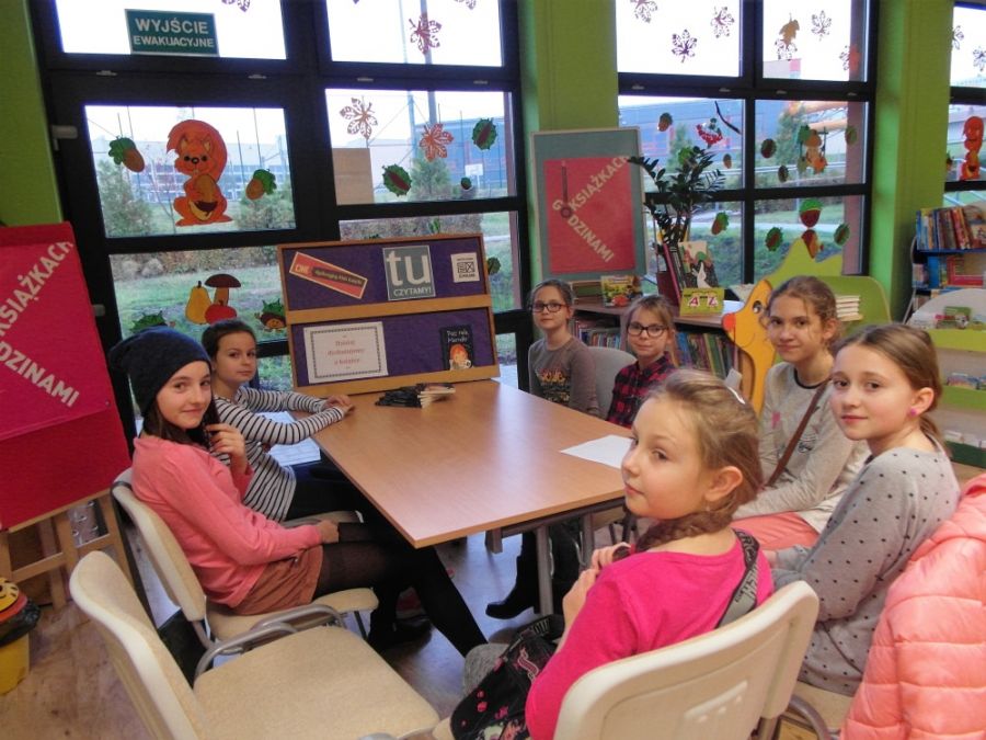 7 dzieci siedzi przy stole i patrzy w stronę obiektywu aparatu