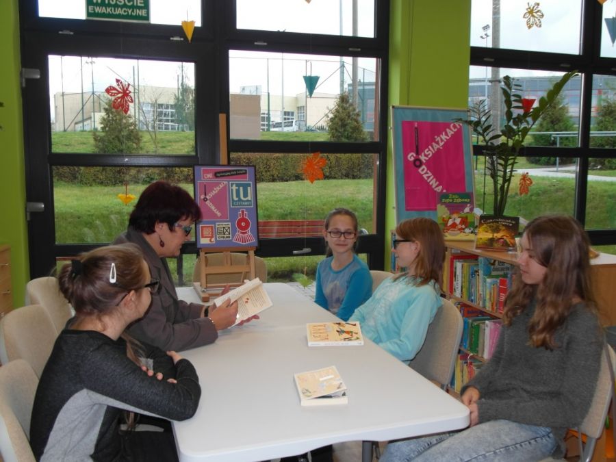 4 uczestniczki spotkania i bibliotekarka siedzą wokół stołu i rozmawiają.