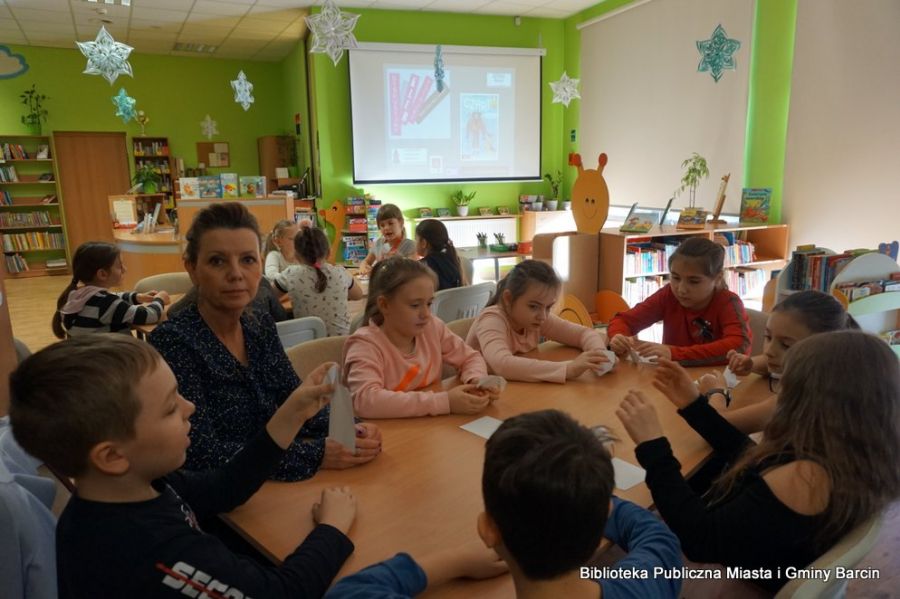 Dzieci uczestniczące w spotkaniu siedzą przy stolikach.