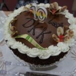 Zdjęcie tortu przygotowanego z okazji 10 rocznicy Dyskusyjnego Klubu Książki w Barcinie, jest to czekoladowy tort z ozdobiony białym kremem i kwiatkami z dwukolorowej czekolady.