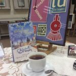 Na zdjęciu widać logotypy partnerów projektu DKK, omawianą książkę oraz filiżankę z herbatą.