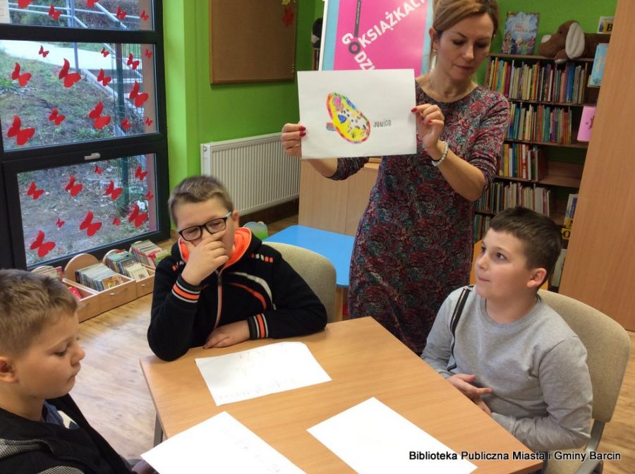Nauczycielka, która przyszła z dziećmi na zajęcia, pokazuje pracę wykonaną przez jednego z chłopców.