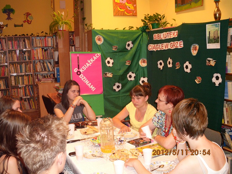 Uczestnicy spotkania siedzą przy stołach i rozmawiają o przeczytanej książce