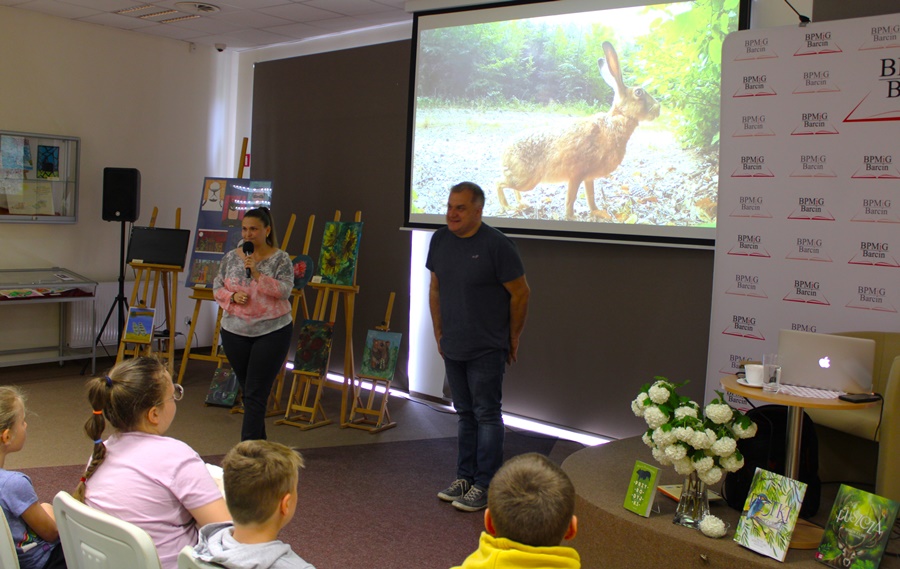 Kierowniczka oddziału dla dzieci i młodzieży razem z Marcinem Kostrzyńskim stoją przed zebraną publicznością i rozpoczynają spotkanie.