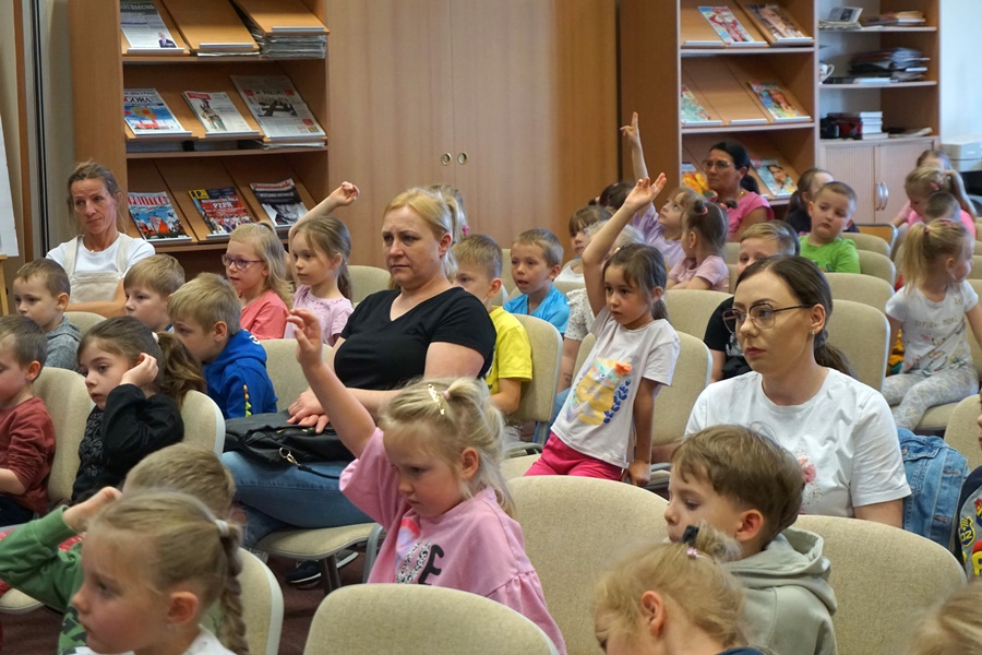 Część widowni, obecnej na spotkaniu, niektóre dzieci podnoszą ręce zgłoaszając się.