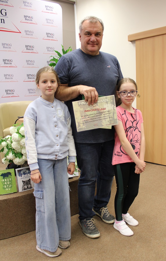 Dwie dziewczynki i zaproszony gość trzymający wręczone podziękowania na wspólnym zdjęciu,