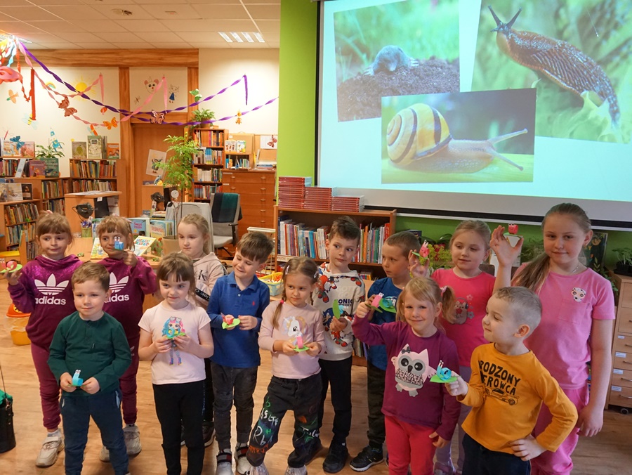 Grupowe zdjęcie dzieci biorących udział w zajęciach trzymają w rękach ślimaki wykonane z papieru