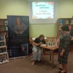 Zaproszona autorka Anet Obarska siedzi przy stoliku i podpisuje ksiażkę