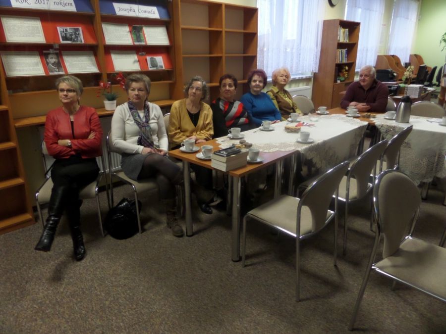 7 osób siedzących na krzesłach patrzy w tę samą stronę