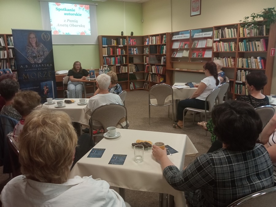osoby zgromadzone w bibliotece z uwagą słuchają tego o czym mówi Aneta Obarska