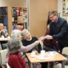Zaproszony gość wręcza jednej z osób nagrodę w postaci książki, którą ta osoba wygrała w konkursie.