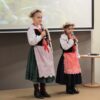 2 uczestniczki przebrane w ludowe stroje występują przed publicznością