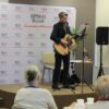 Pan Michał stoi na scenie z gitarą w rękach i recytuje swoje wiersze.