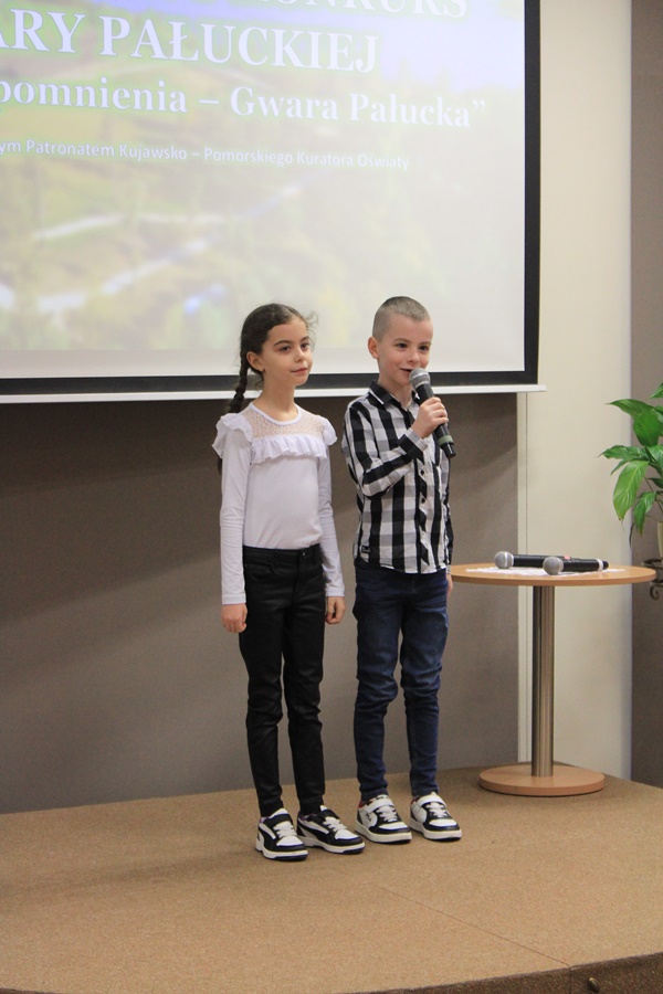2 uczestników z pierwszej kategorii wiekowej stoi na scenie i występuje przed publicznością