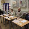 jury konkursu, dwie kobiety i mężczyzna siedzący przy kwadratowych stolikach