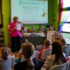 bibliotekarka stojąca przed zebraną publicznością pokazuje blankiet, do którego bingo używano w trakcie konkursu