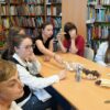 młodzież siedząca przy stole w czasie spotkania częstuje się potrawami przygotowanymi z tej okazji