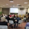 na pierwszym planie widownia i uczestnicy konkursu, w głębi widać ekran projektora na którym wyświetlane sa pytania