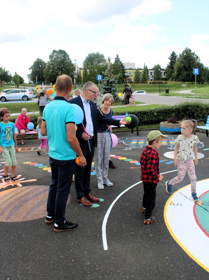 dorośli obserwujący dzieci korzystające z gry chodnikowej