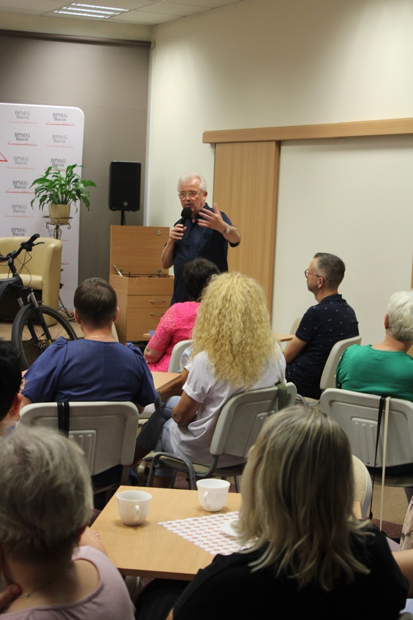 Ksiądz kanonik stoi z mikrofonem w ręce i mówi coś do publiczności