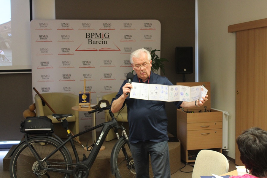 Zaproszony gość prezentuje publiczności paszport pielgrzyma