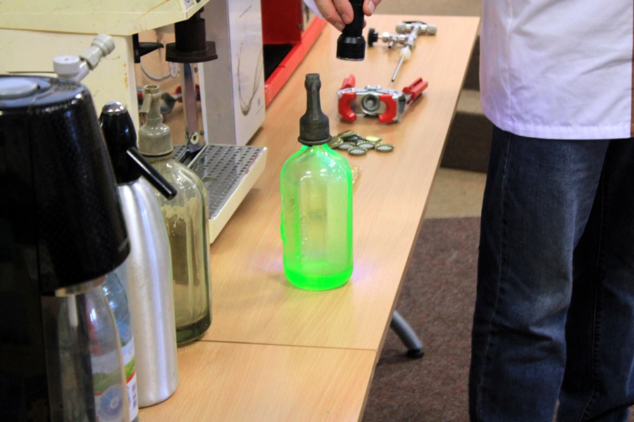 Syfon wykonany ze szkła uranowego świeci na zielono pod wpływem światła ultra fioletowego