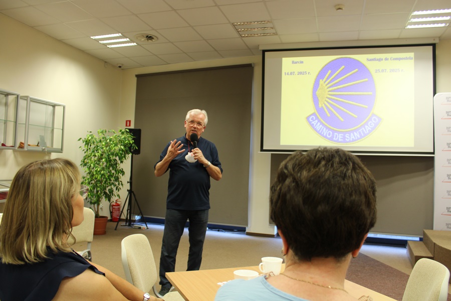 Ksiądz kanonik stoi z mikrofonem w ręce i mówi coś do publiczności