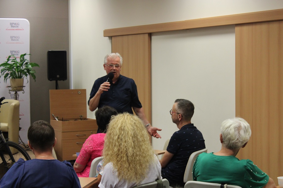 Ksiądz kanonik stoi z mikrofonem w ręce i mówi coś do publiczności