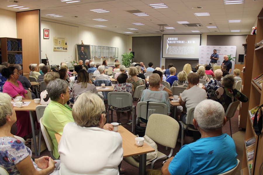 Liczna publiczność zgromadzona w sali z uwagą słucha opowieści o pielgrzymce