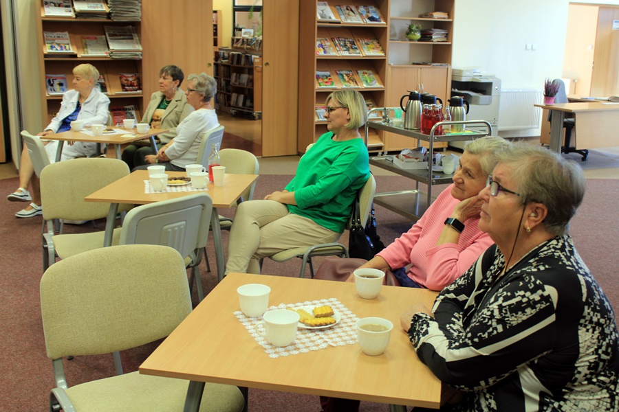 widzowie siedzą przy stolikach z kawą i herbatą, słuchają rozmowy prowadzonej z autorem