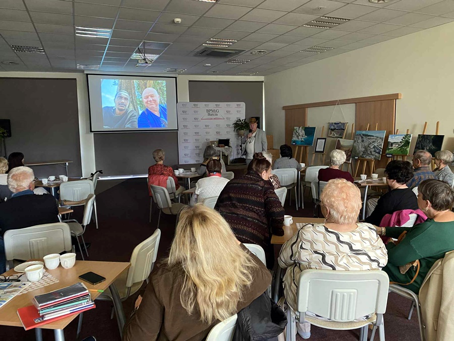 Zebrana publiczność słucha prelegenta i jego opowieści z podróży