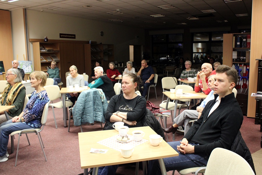 widowania siedzi przy stolikach i słucha prelekcji zaproszonego gościa