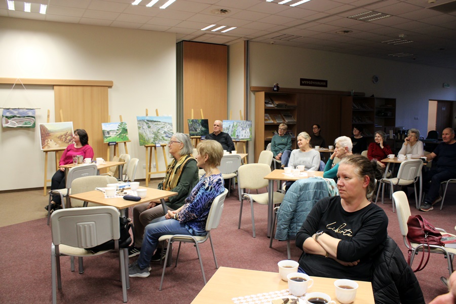 widownia siedząca na krzesłach przy stolikach słucha zaproszonego gościa