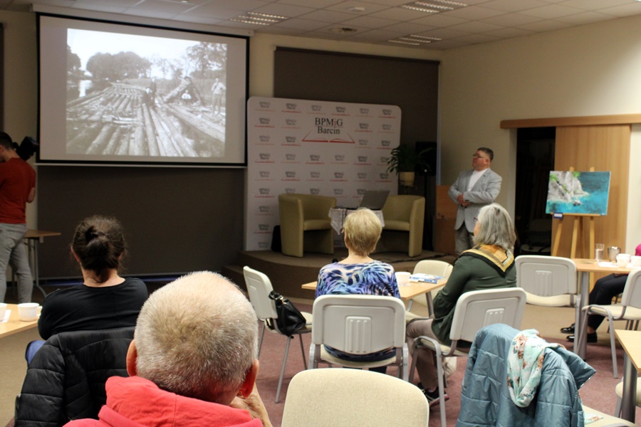 widownia siedząca na krzesłach przy stolikach słucha zaproszonego gościa