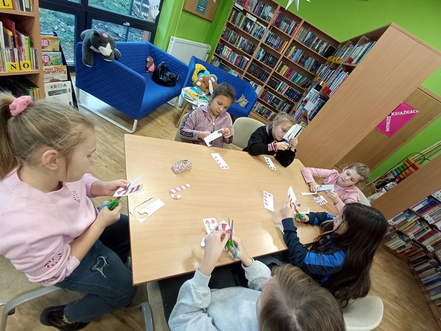 Uczestnicy zajęć wykonują papierowe ozdoby świąteczne