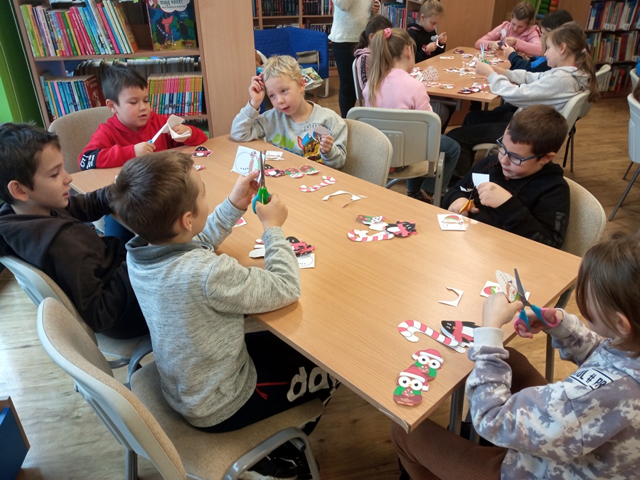 Uczestnicy zajęć wykonują papierowe ozdoby świąteczne