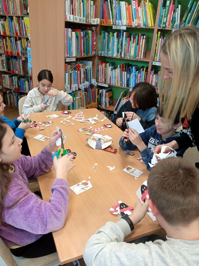 Uczestnicy zajęć wykonują papierowe ozdoby świąteczne