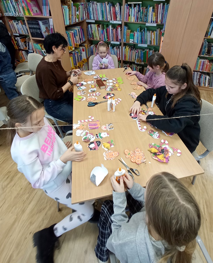 Uczestnicy zajęć wykonują papierowe ozdoby świąteczne