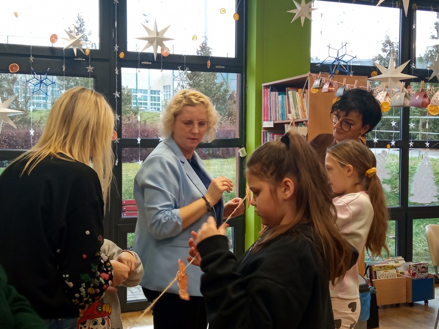 Dzieci i dorośli mocują ozdoby na sznurku