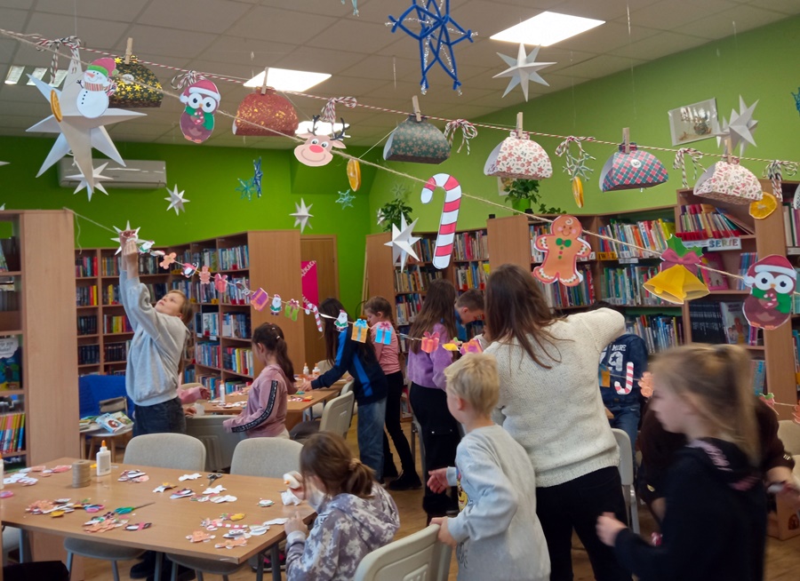 Osoby obecne w czasie zajęć zakładają kolorowe ozdoby na sznurku