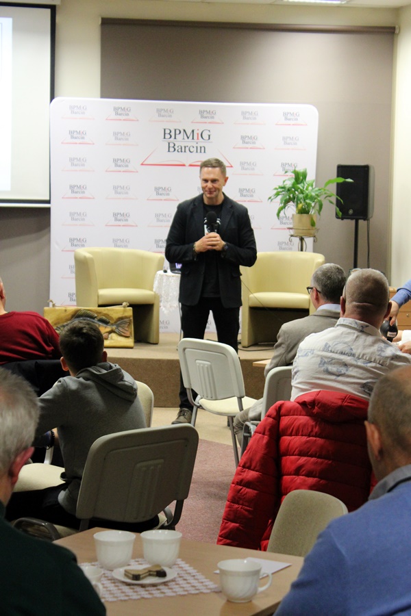 Pan Adam Tański stoi przed publicznością i opowiada o swojej pasji