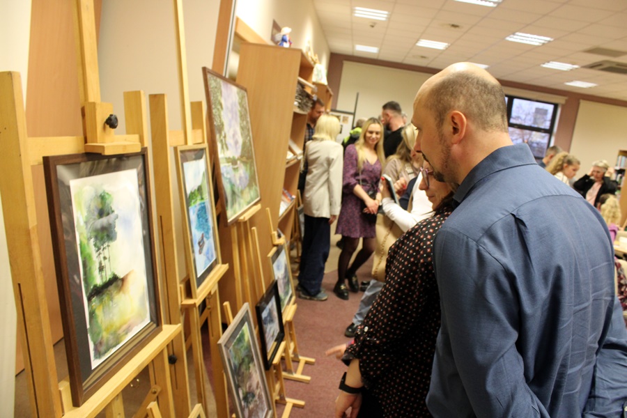 Osoby obecne na spotkaniu oglądają namalowane przez artystkę obrazy