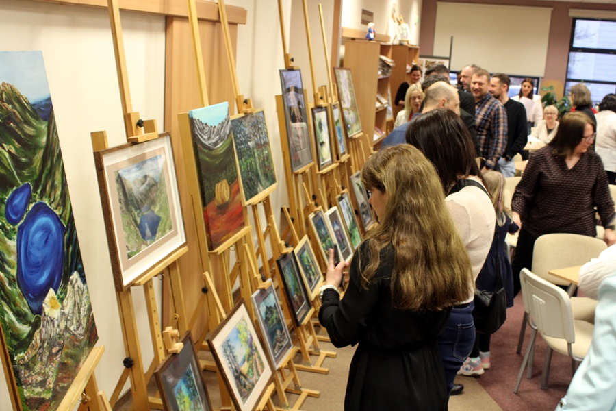 Osoby obecne na spotkaniu oglądają namalowane przez artystkę obrazy