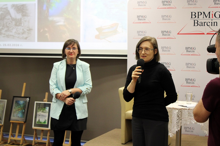 Prowadząca spotkanie stoi razem z zaproszonym gościem, wita zebraną publicznosć.