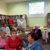 Uczestnicy spotkania siedzą wokół prostokątnych stołów