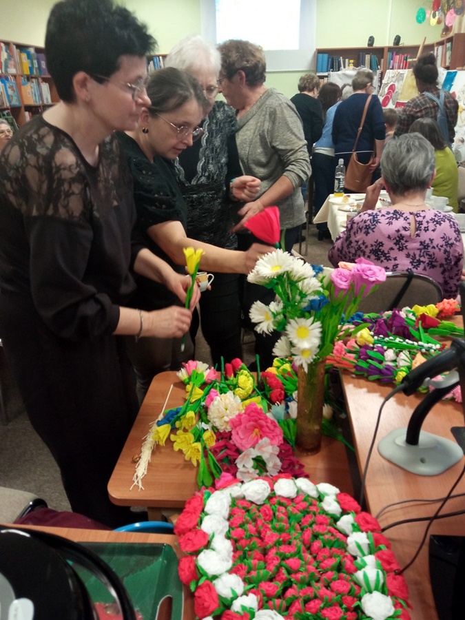 Obecni na wydarzeniu ludzie oglądają wystawę ustawioną w bibliotece