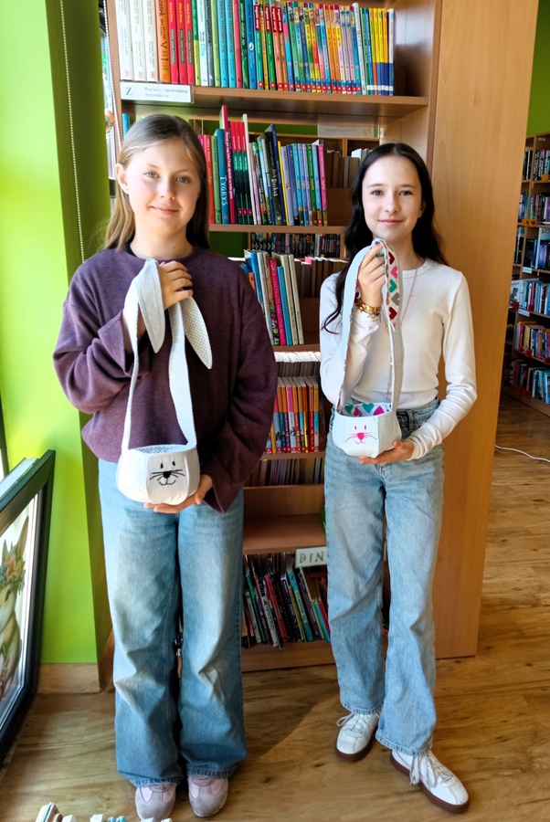 Uczestniczki warsztatów trzymają wykonane podczas zajęć koszyki materiałowe z motywem zajączka