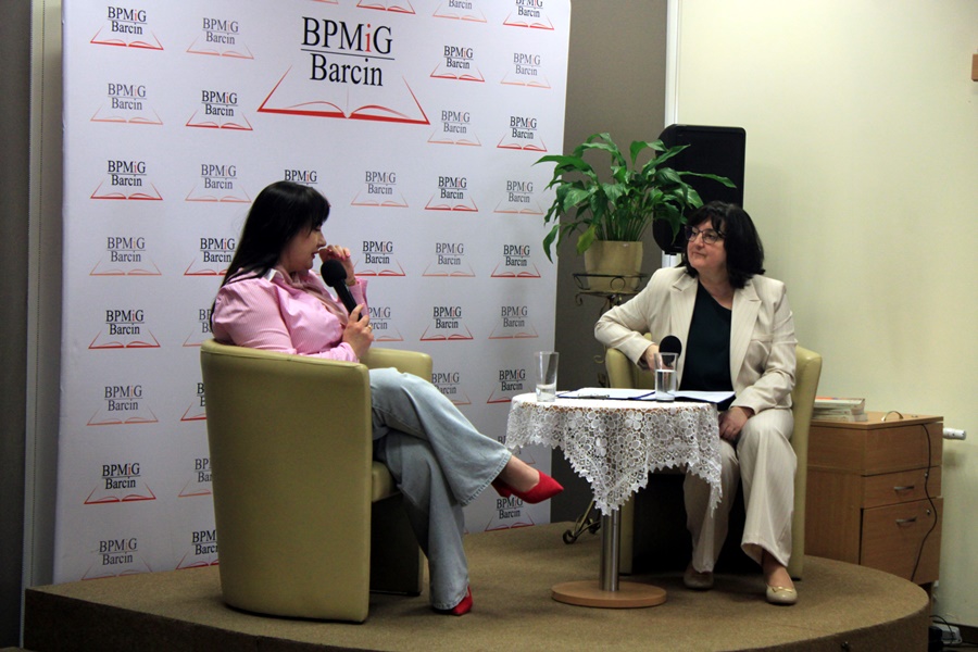 dyrektorka biblioteki rozmawia z zaproszoną gościnią. kobiety siedza na podwyższeniu