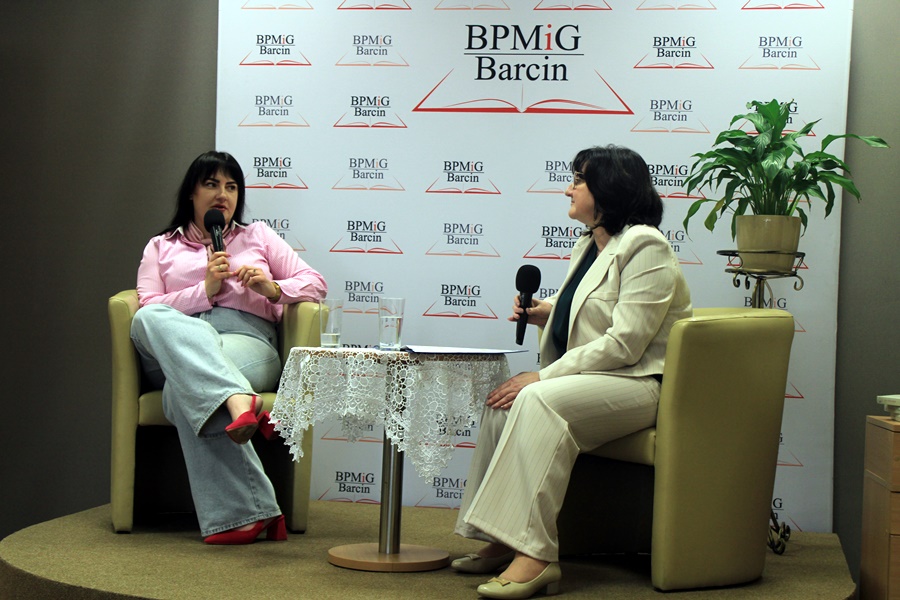 dyrektorka biblioteki rozmawia z zaproszoną gościnią. kobiety siedza na podwyższeniu