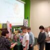 Dzieci podchodzą do stoliak przy, którym siedzi zaproszona pisarka i podpisuje książki